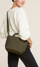 Load image into Gallery viewer, Woman standing with Naghedi handwoven neoprene St. Barths Small Tote bag in Olive green, available at Amara Home.