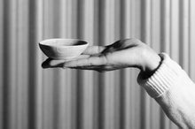 Load image into Gallery viewer, Hand holding Wonki Ware unique ceramic salt dish with black textured glaze, handmade in South Africa, available at Amara Home.